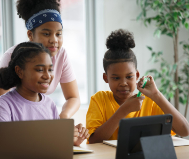 portrait-brilliant-black-girl-with-braces-writes-exercise-notebook-smiles-junior-classroom-with-diverse-group-children-learning-new-stuff