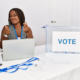 young-african-american-woman-working-political-election-sitting-by-ballot-doing-money-gesture-with-hands-asking-salary-payment-millionaire-business (1)